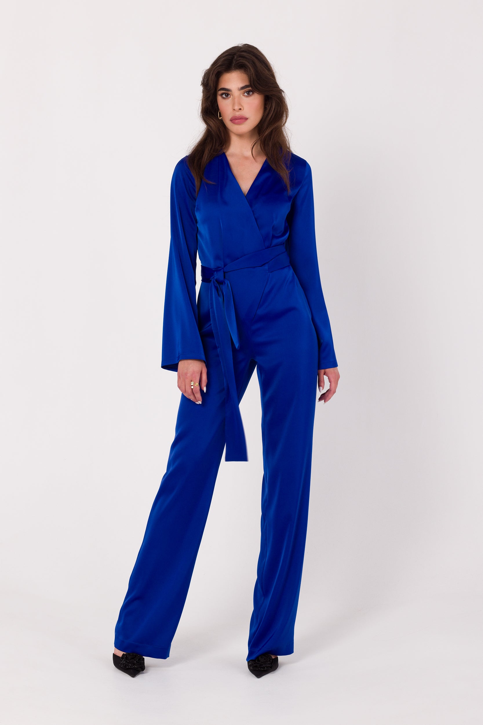Long Sleeve Blue Satin Jumpsuit | Strictly In | Make a statement at your next event with our Long Sleeve Satin Jumpsuit. Crafted from luxurious satin, it features a V-neck, long sleeves, and a tied waist for a glamorous yet comfortable look. Perfect for the party season.