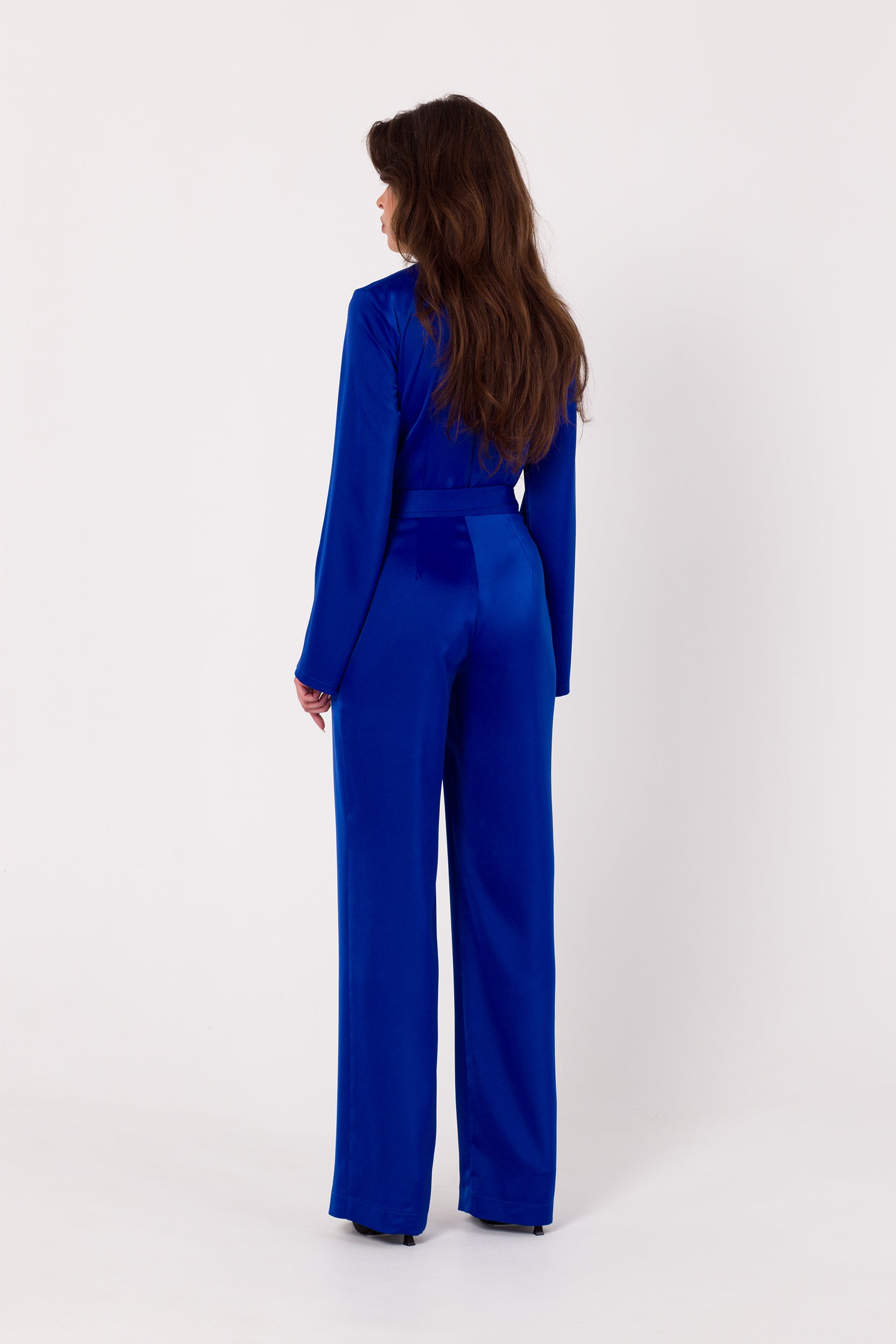Long Sleeve Blue Satin Jumpsuit | Strictly In | Make a statement at your next event with our Long Sleeve Satin Jumpsuit. Crafted from luxurious satin, it features a V-neck, long sleeves, and a tied waist for a glamorous yet comfortable look. Perfect for the party season.
