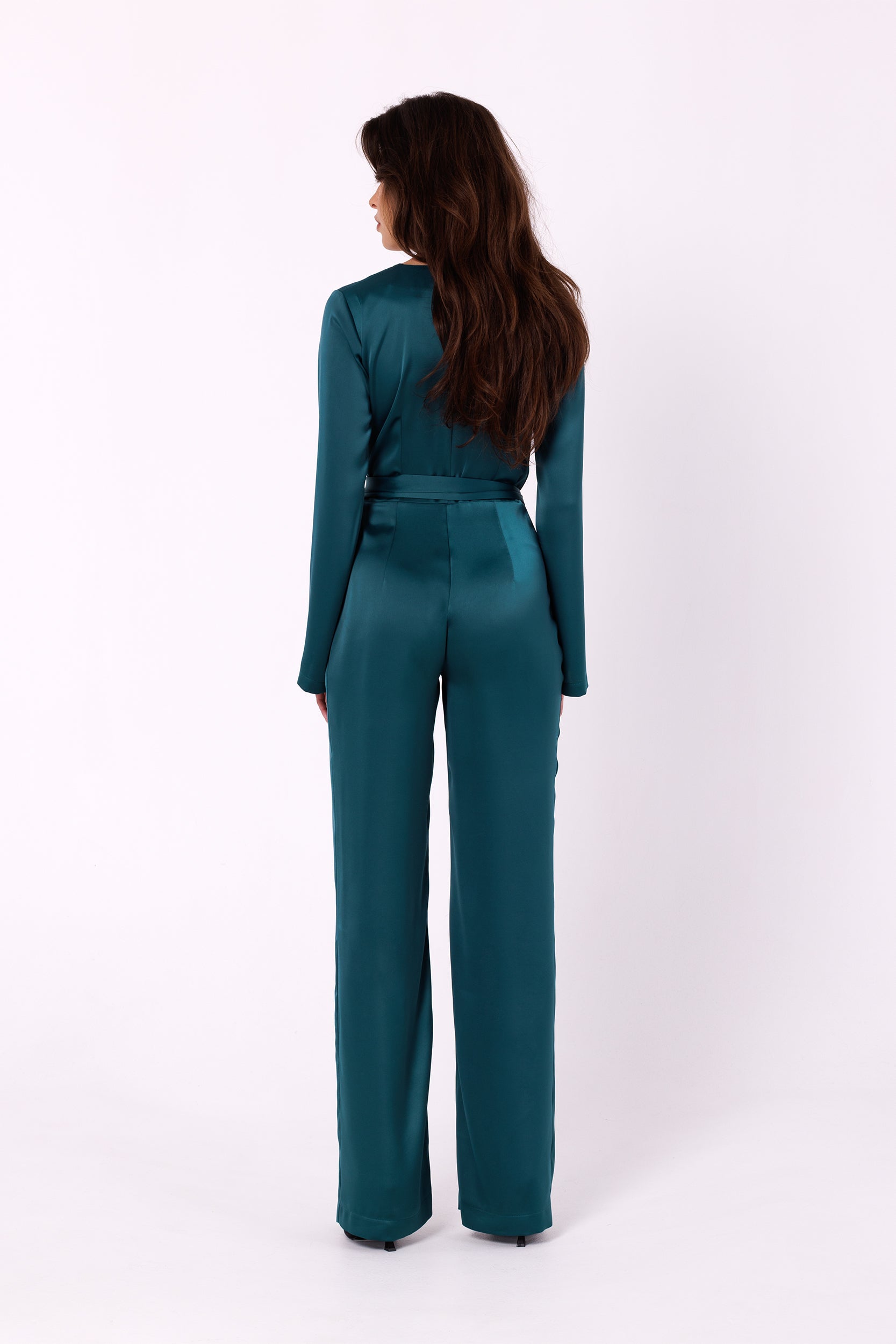 Long Sleeve Green Jumpsuit | Strictly In | Make a statement at your next event with our Long Sleeve Satin Jumpsuit. Crafted from luxurious satin, it features a V-neck, long sleeves, and a tied waist for a glamorous yet comfortable look. Perfect for the party season.