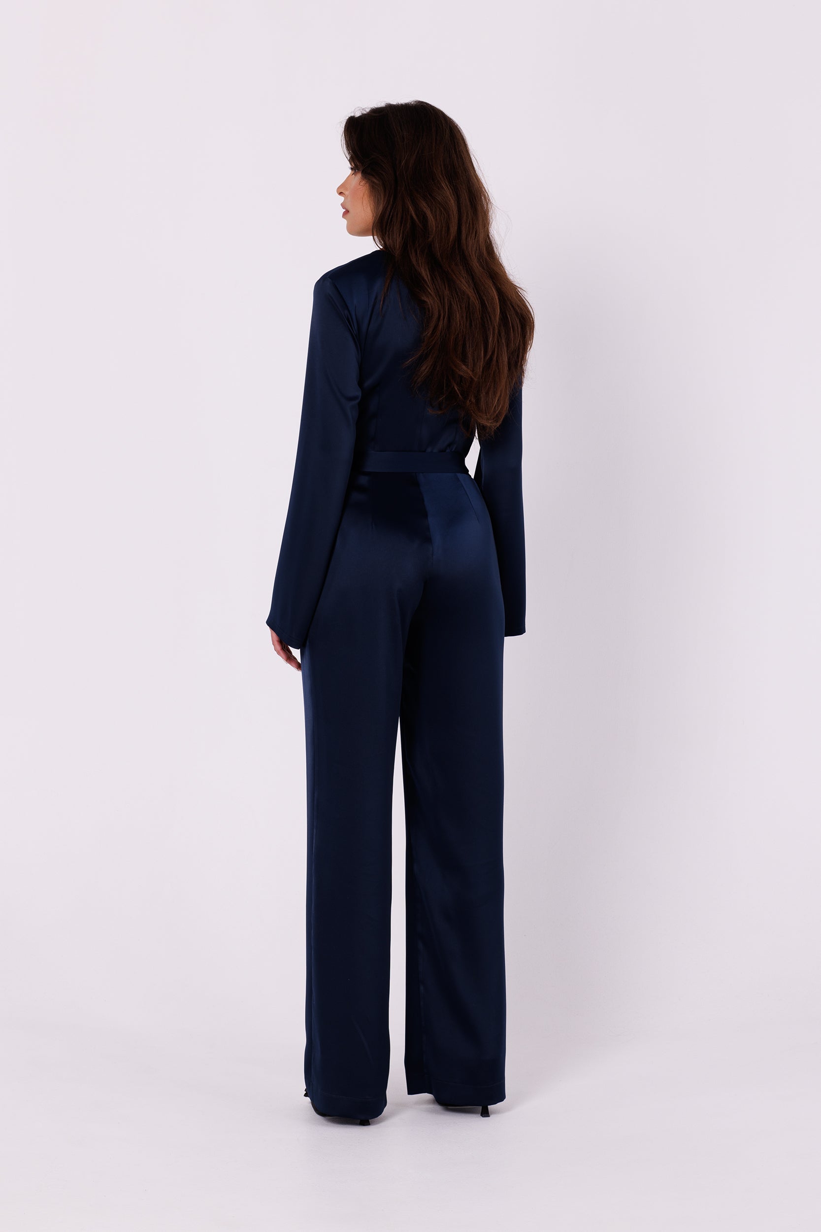Long Sleeve Night Blue Satin Jumpsuit | Strictly In | Make a statement at your next event with our Long Sleeve Satin Jumpsuit. Crafted from luxurious satin, it features a V-neck, long sleeves, and a tied waist for a glamorous yet comfortable look. Perfect for the party season.